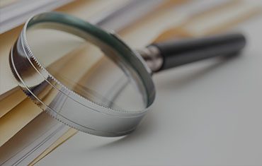 Magnifying glass on stacked documents.